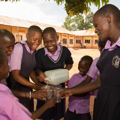Children at St Balikuddembe school enjoying water from their new tank - Copyright All We Can